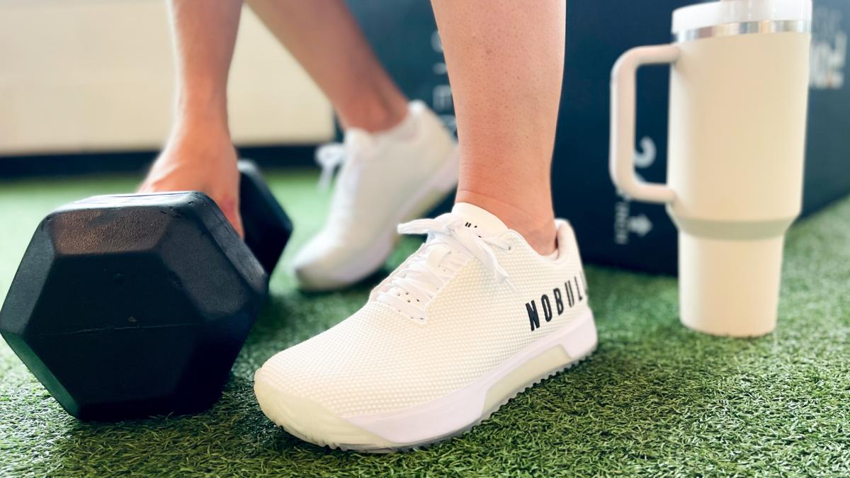 Close up image of athlete wearing Nobull Trainer+ Shoes and grabbing a dumbbell.